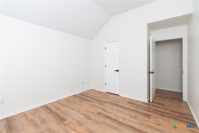 unfurnished bedroom featuring light hardwood / wood-style floors and lofted ceiling