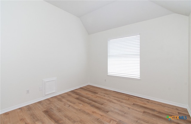 empty room with vaulted ceiling and light hardwood / wood-style flooring