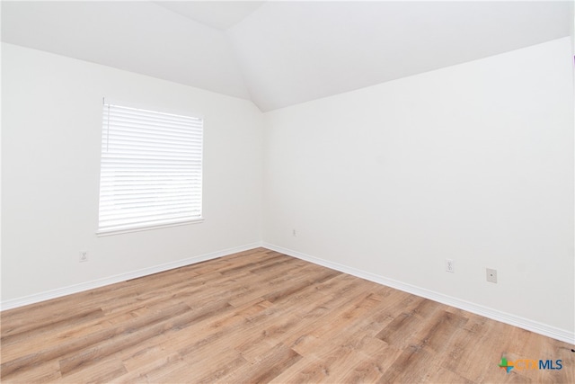 spare room featuring light wood-type flooring and lofted ceiling