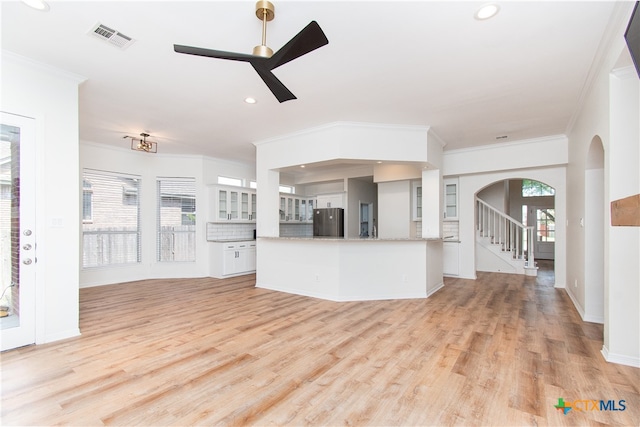 unfurnished living room featuring light hardwood / wood-style floors, ceiling fan, and ornamental molding