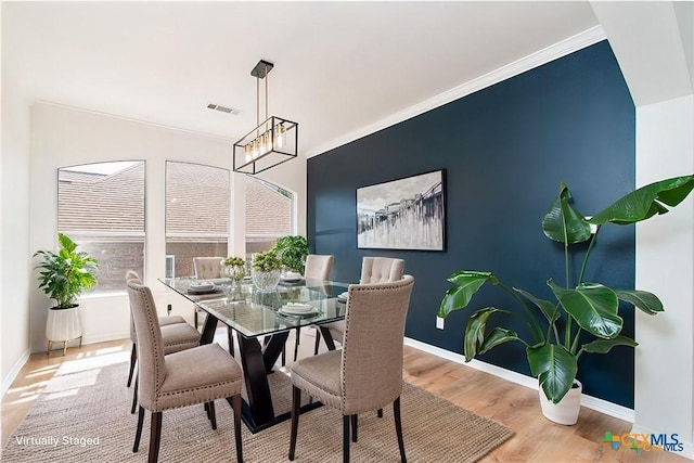 dining area featuring light hardwood / wood-style floors, a notable chandelier, and crown molding