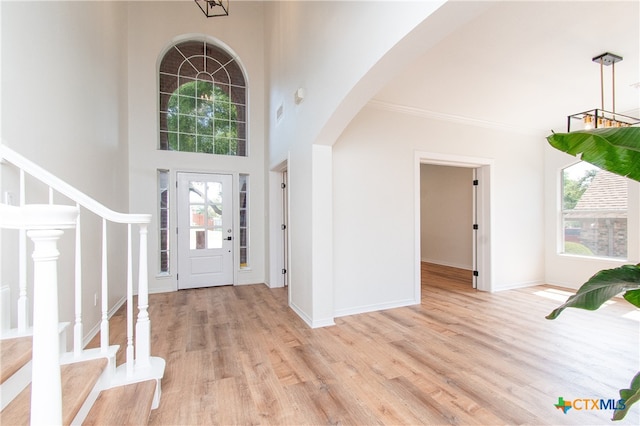 foyer featuring a high ceiling, light hardwood / wood-style flooring, and a chandelier