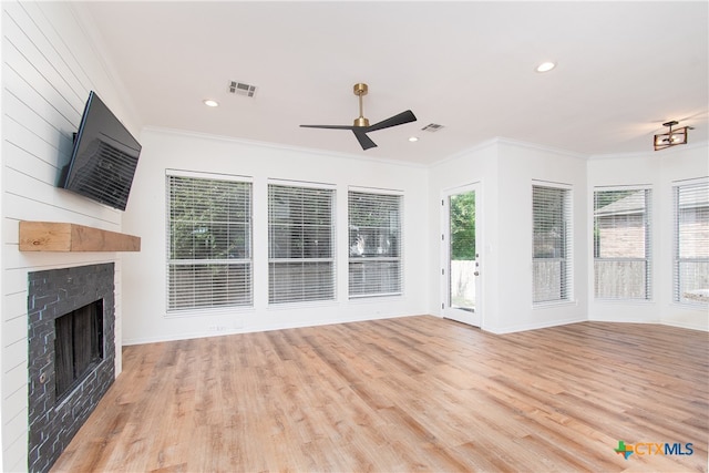 unfurnished living room with ceiling fan, light wood-type flooring, crown molding, and a fireplace