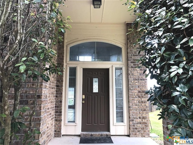 entrance to property featuring brick siding