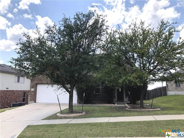 obstructed view of property with a garage, brick siding, fence, driveway, and a front lawn