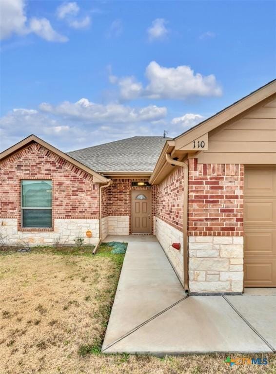 view of exterior entry with a garage and a yard