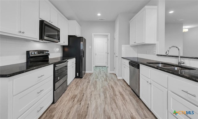 kitchen with light hardwood / wood-style floors, appliances with stainless steel finishes, dark stone countertops, white cabinets, and sink