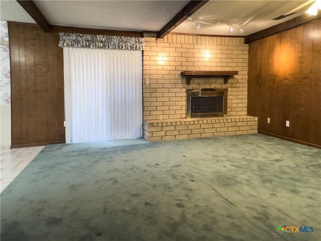 unfurnished living room featuring beamed ceiling, a textured ceiling, a fireplace, and wooden walls