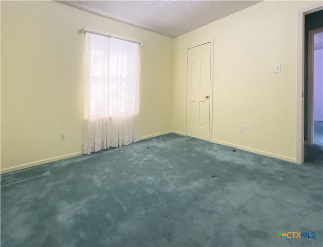 spare room with dark colored carpet and a textured ceiling