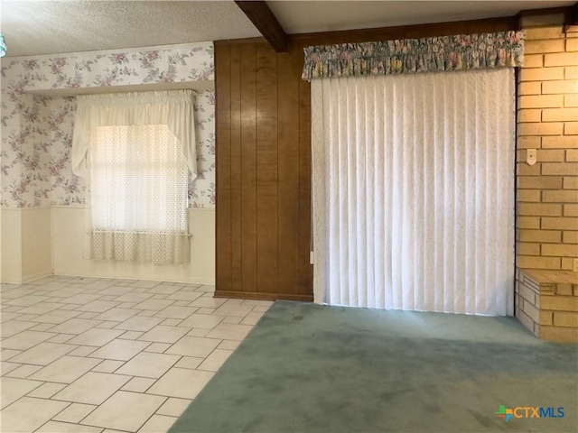 unfurnished room with beam ceiling, wood walls, and a textured ceiling