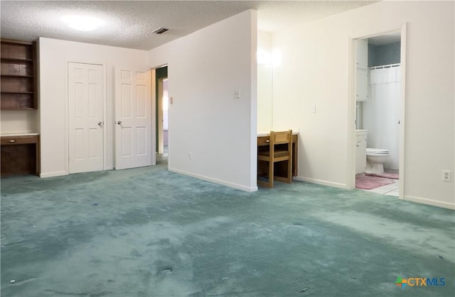 unfurnished bedroom featuring ensuite bathroom, carpet, and a textured ceiling