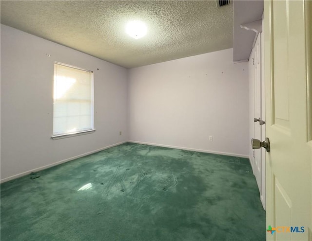 spare room with dark colored carpet and a textured ceiling