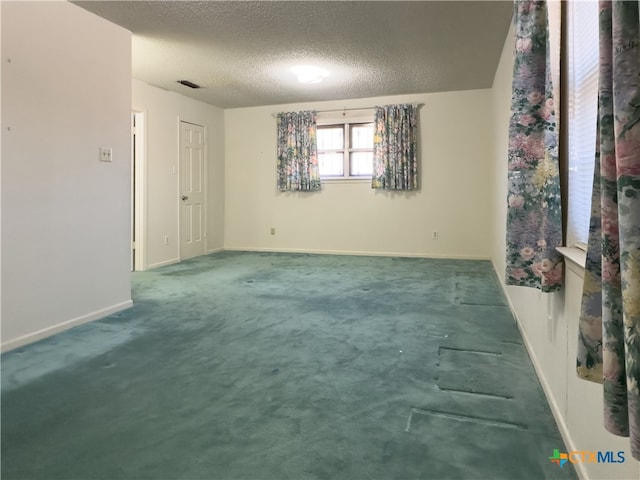 unfurnished room featuring carpet and a textured ceiling