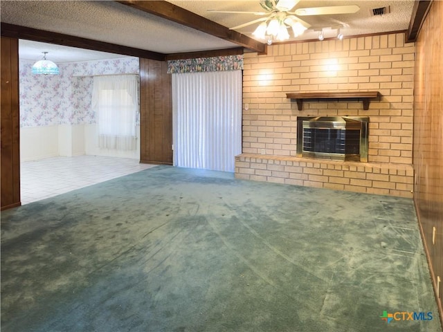 unfurnished living room with beam ceiling, carpet, a textured ceiling, and a brick fireplace