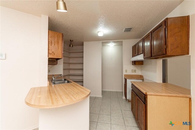 5111 Anacacho St, San Antonio, TX 78217 - kitchen with light countertops, a sink, a textured ceiling, light tile patterned floors, and baseboards