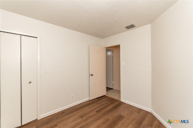 5111 Anacacho St, San Antonio, TX 78217 - unfurnished bedroom featuring wood finished floors, a closet, baseboards, and a textured ceiling