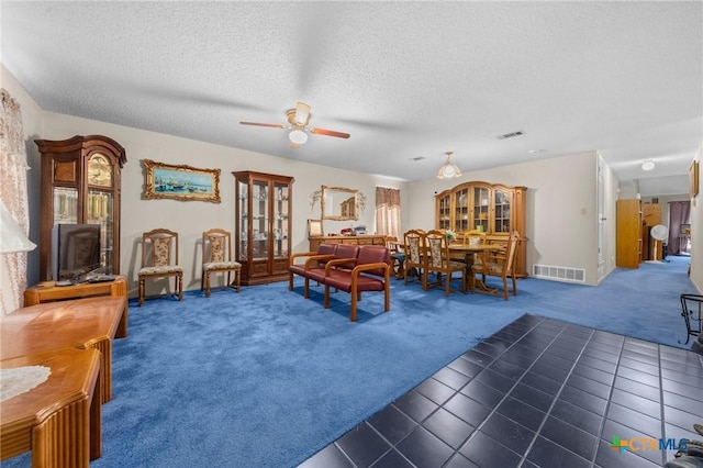 living room with a wood stove, a textured ceiling, dark carpet, and ceiling fan