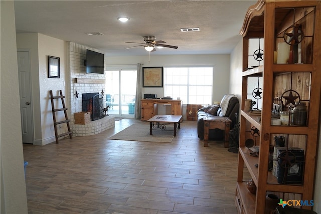 living room featuring ceiling fan, dark hardwood / wood-style flooring, and a brick fireplace