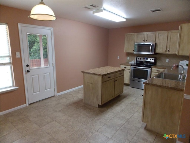 513 Pumpkin Dr, Temple, TX 76502 - kitchen featuring appliances with stainless steel finishes, light brown cabinetry, a kitchen island, decorative backsplash, and decorative light fixtures