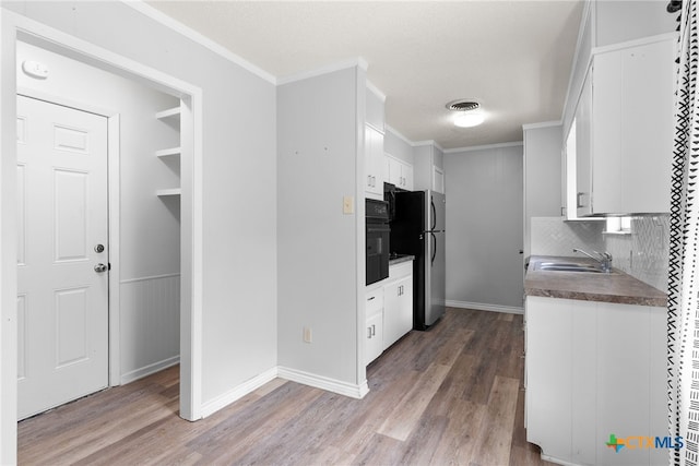 kitchen with white cabinetry, hardwood / wood-style floors, oven, and stainless steel refrigerator