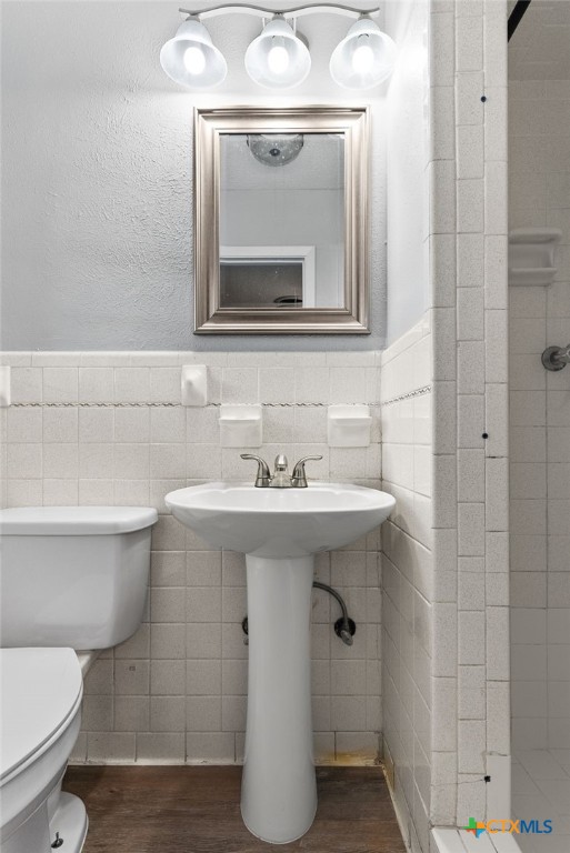 bathroom featuring hardwood / wood-style floors, toilet, and tile walls