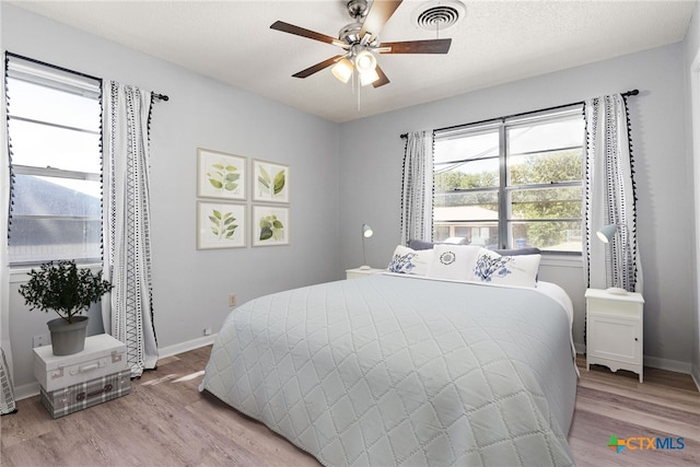 bedroom with light hardwood / wood-style floors, ceiling fan, and a textured ceiling