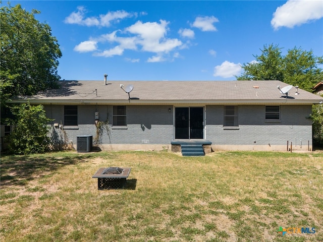 back of property featuring central air condition unit, a yard, and an outdoor fire pit