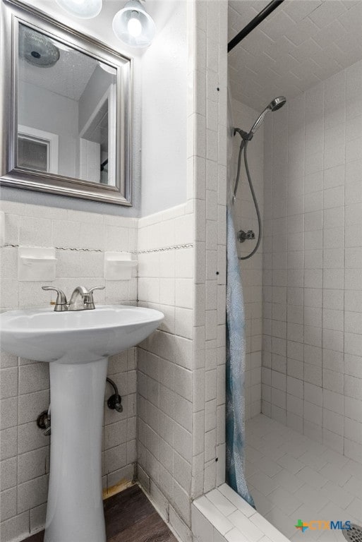 bathroom with tile walls, sink, and a tile shower