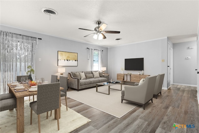 living room with hardwood / wood-style flooring, ceiling fan, a textured ceiling, and ornamental molding