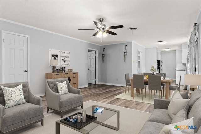 living room with hardwood / wood-style floors, ceiling fan, and ornamental molding