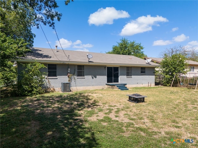 back of property featuring central air condition unit, an outdoor fire pit, and a yard