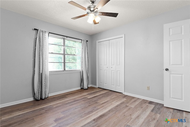 unfurnished bedroom featuring a textured ceiling, light wood-type flooring, ceiling fan, and a closet