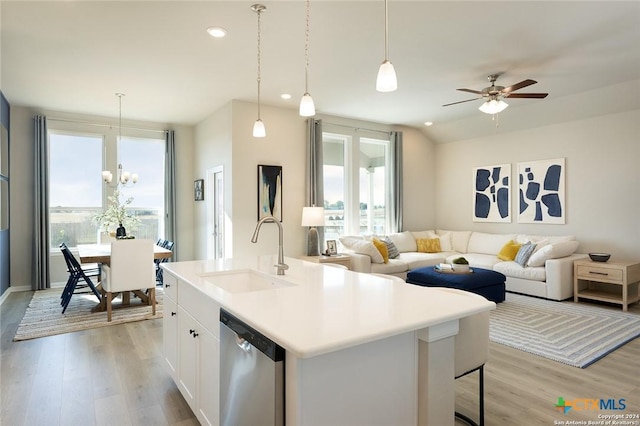 kitchen with pendant lighting, sink, a kitchen island with sink, white cabinets, and stainless steel dishwasher