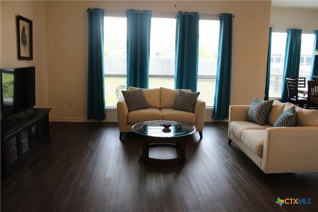 living room featuring dark wood-style flooring, plenty of natural light, and baseboards