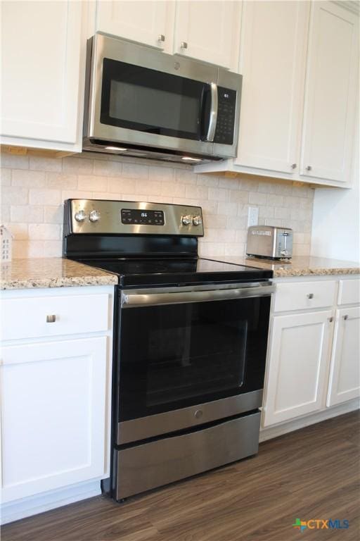 kitchen featuring light stone counters, dark wood-style flooring, appliances with stainless steel finishes, and white cabinetry