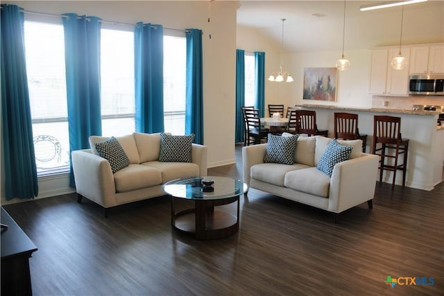 living room with a notable chandelier, dark wood-style floors, and baseboards