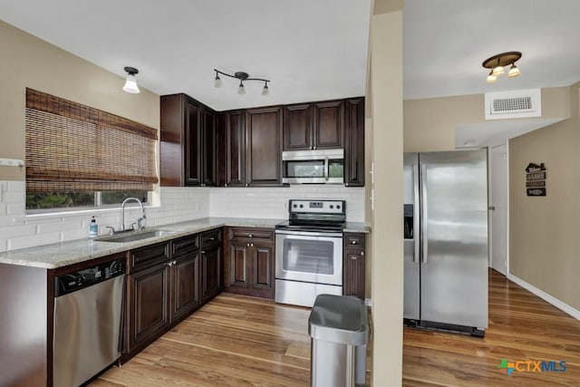 1568 Blueridge Dr, Canyon Lake, TX 78133 - kitchen with stainless steel appliances, light wood-type flooring, tasteful backsplash, and dark brown cabinets