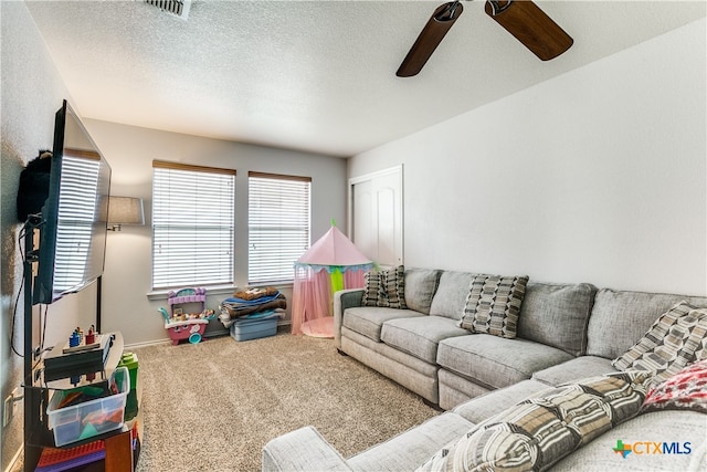 living room with a textured ceiling, carpet floors, and ceiling fan