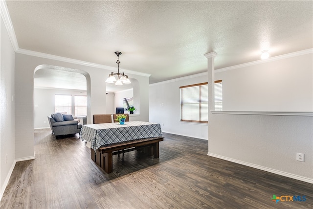 dining space featuring ornamental molding, dark wood-type flooring, a textured ceiling, and an inviting chandelier