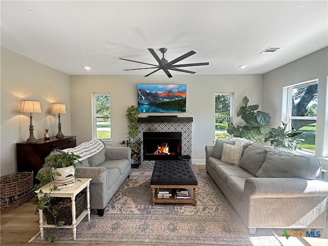 701 S Hudson St, Flatonia, TX 78941 - living room with a tile fireplace, wood finished floors, plenty of natural light, a ceiling fan, and a textured ceiling