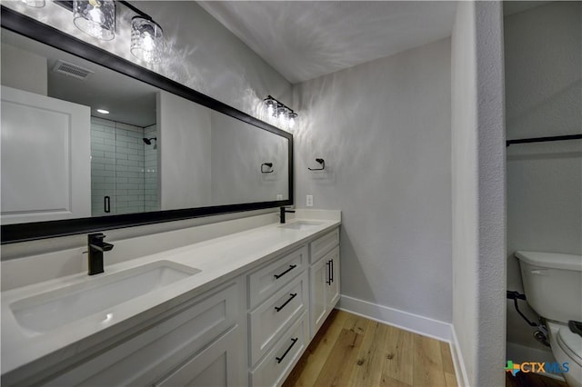 701 S Hudson St, Flatonia, TX 78941 - bathroom with wood finished floors, toilet, baseboards, double vanity, and a stall shower