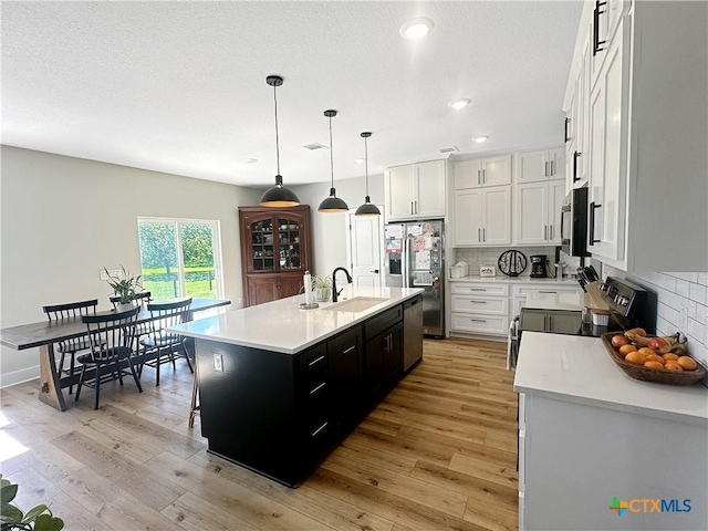 701 S Hudson St, Flatonia, TX 78941 - kitchen featuring a sink, stainless steel appliances, light countertops, tasteful backsplash, and light wood-style floors
