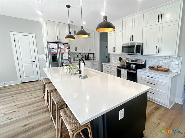 701 S Hudson St, Flatonia, TX 78941 - kitchen featuring appliances with stainless steel finishes, a sink, light wood-type flooring, tasteful backsplash, and recessed lighting