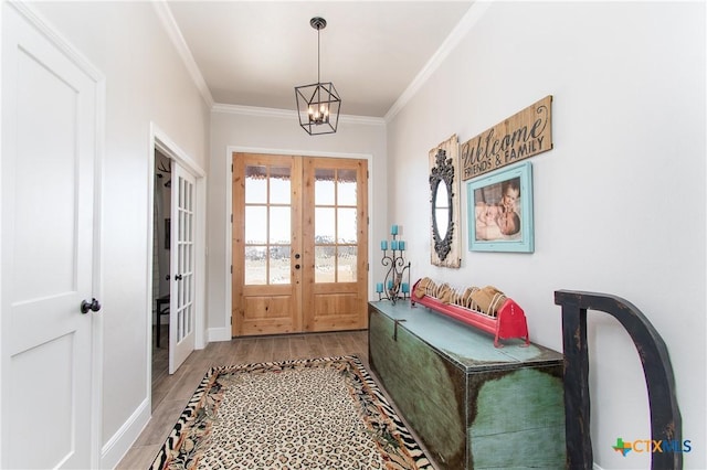 entryway with hardwood / wood-style flooring, a chandelier, ornamental molding, and french doors