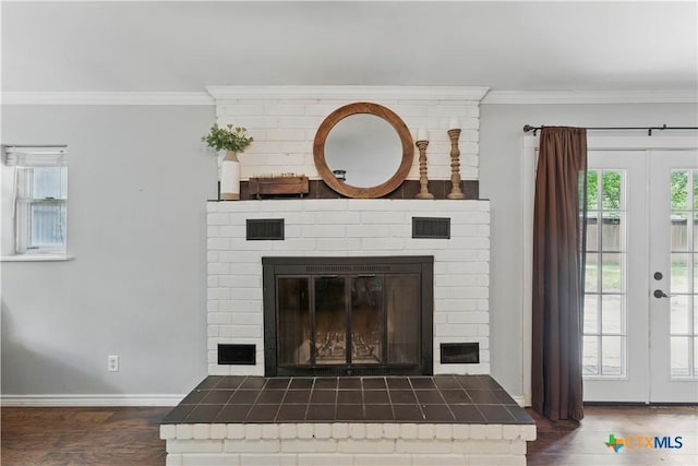 details with a brick fireplace, baseboards, wood finished floors, visible vents, and ornamental molding