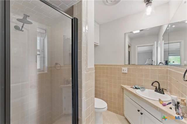 bathroom featuring vanity, toilet, tile walls, tile patterned floors, and a shower stall