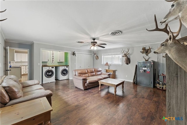living area featuring ornamental molding, a ceiling fan, dark wood-type flooring, visible vents, and washing machine and dryer