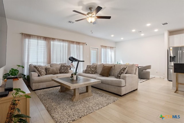 living room with a wealth of natural light, ceiling fan, and light wood-type flooring