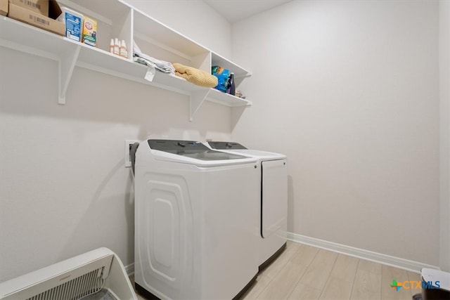 laundry room with washing machine and dryer and light hardwood / wood-style floors