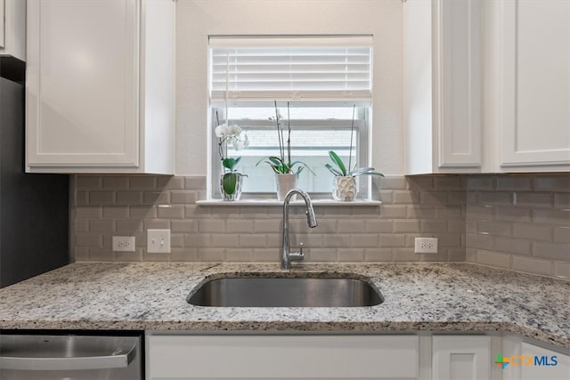 kitchen featuring light stone countertops, white cabinetry, sink, and decorative backsplash